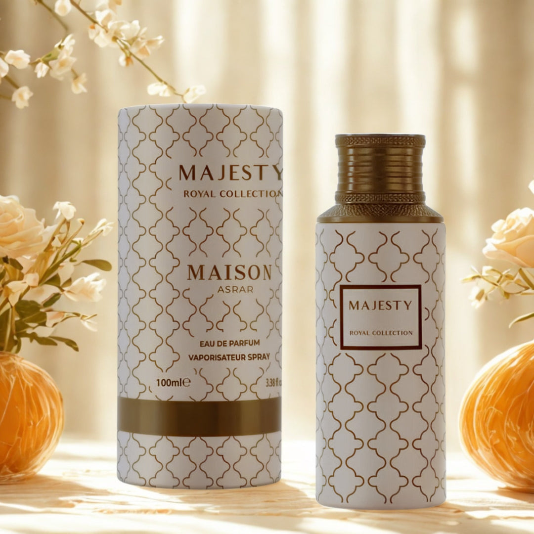 Maison Asrar Majesty bottle and round box in a cream and gold colourway beside flowers